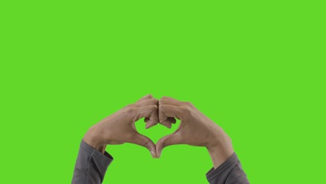 Studio-Close-Up-Shot-Of-Woman-Making-Heart-Shape-Symbol-For-Love-Against-Green-Screen-1