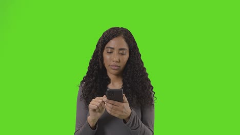 Woman-Looking-At-Mobile-Phone-And-Celebrating-Good-News-Against-Green-Screen
