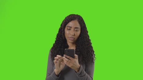 Woman-Looking-At-Mobile-Phone-And-Celebrating-Good-News-Against-Green-Screen-1