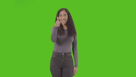 Studio-Three-Quarter-Length-Shot-Of-Woman-Giving-Thumbs-Up-Sign-Against-Green-Screen