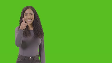 Studio-Waist-Up-Shot-Of-Woman-Giving-Thumbs-Up-Sign-Against-Green-Screen