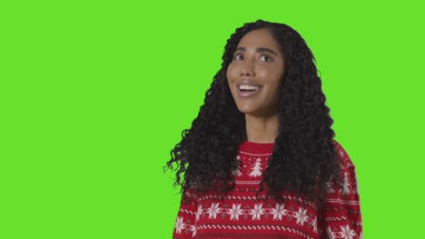 Studio-Portrait-Of-Woman-Wearing-Christmas-Jumper-Against-Green-Screen-With-Hands-Out-To-Catch-Falling-Snow