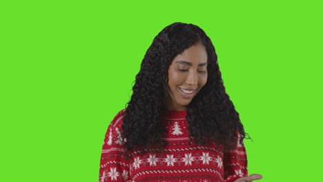 Studio-Portrait-Of-Woman-Wearing-Christmas-Jumper-Against-Green-Screen-With-Hands-Out-To-Catch-Falling-Snow-1