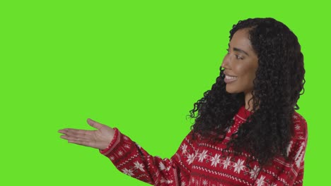 Studio-Portrait-Of-Woman-Wearing-Christmas-Jumper-Showing-Item-Or-Object-Against-Green-Screen-Smiling-At-Camera-1
