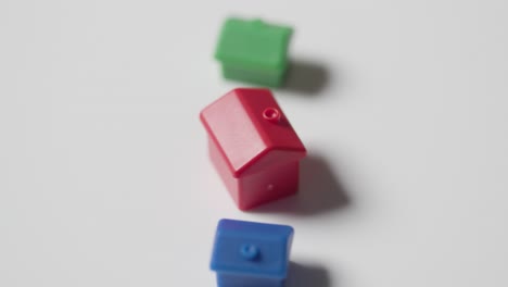 Home-Buying-Concept-With-Red-Blue-And-Green-Plastic-Models-Of-Houses-Revolving-On-White-Background