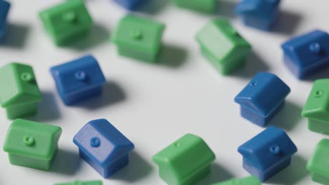 Home-Buying-Concept-With-Blue-And-Green-Plastic-Models-Of-Houses-Revolving-On-White-Background-