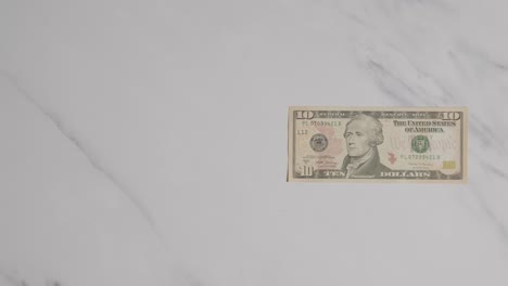 Overhead-Currency-Shot-Of-Hand-Grabbing-US-10-Dollar-Bill-On-Marble-Surface-1