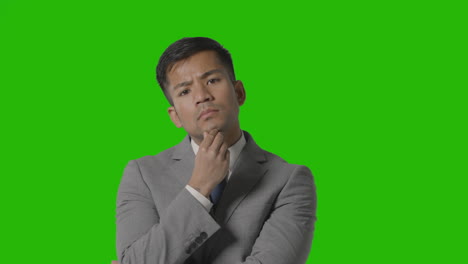 Portrait-Of-Serious-Businessman-In-Suit-Thinking-Against-Green-Screen-Looking-At-Camera