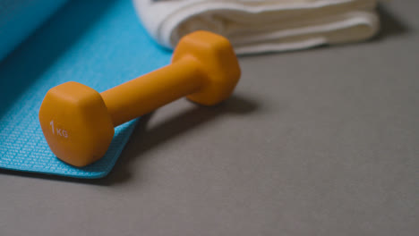 Close-Up-Fitness-Studio-Shot-Of-Exercise-Dumbbell-Weight-And-Water-Bottle-With-Towel-And-Mat