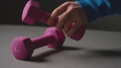 Close-Up-Studio-Fitness-Shot-Of-Hand-Picking-Up-Pink-Gym-Weight-On-Grey-Background