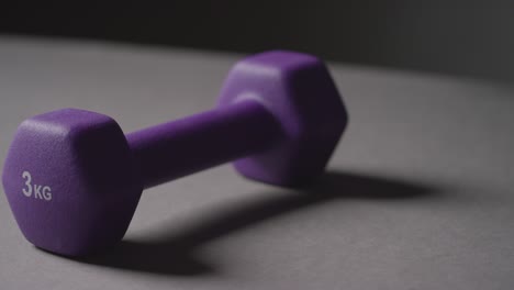 Close-Up-Studio-Fitness-Shot-Of-Hand-Picking-Up-Purple-Gym-Weight-On-Grey-Background-1