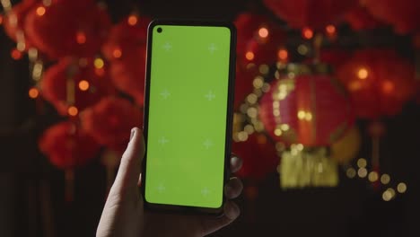 Hand-Mit-Greenscreen-Handy-Mit-Chinesischen-Laternen-Im-Hintergrund-4