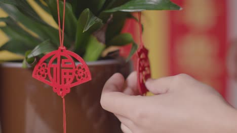 Close-Up-Of-Woman-Hanging-Decorations-Celebrating-Chinese-New-Year-On-Plants-At-Home-2