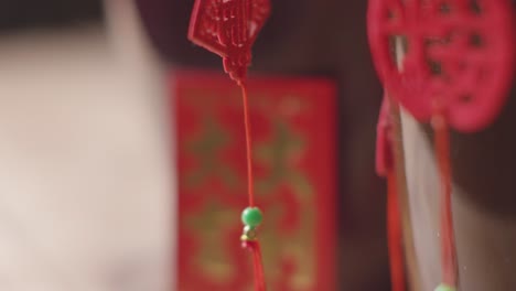 Close-Up-Of-Decorations-Celebrating-Chinese-New-Year-Hanging-On-Plant-With-Card-At-Home-