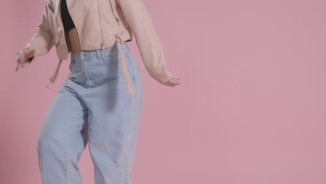 Close-Up-On-Legs-Of-Woman-Having-Fun-Dancing-Against-Pink-Studio-Background