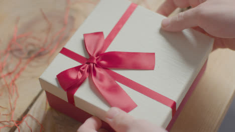 Close-Up-Shot-Of-Man-Gift-Wrapping-Romantic-Valentines-Present-Of-Perfume-In-Box-On-Table