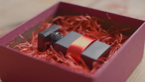 Close-Up-Shot-Of-Romantic-Valentines-Present-Of-Perfume-Gift-Wrapped-In-Box-On-Table-
