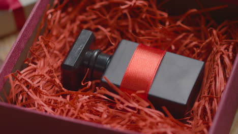 Close-Up-Shot-Of-Man-Gift-Wrapping-Romantic-Valentines-Present-Of-Perfume-In-Box-On-Table-2