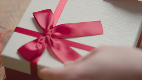 Close-Up-Shot-Of-Man-Gift-Wrapping-Romantic-Valentines-Present-Of-Perfume-In-Box-On-Table-3
