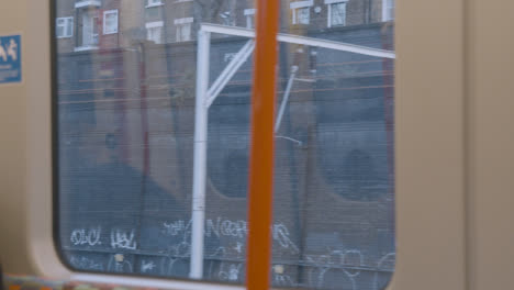 Urban-View-From-Commuter-Train-Window-With-Graffiti-And-Electric-Power-Lines