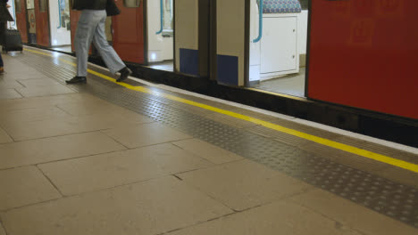 Primer-Plano-Del-Tren-Subterráneo-Que-Llega-A-La-Plataforma-De-La-Estación-De-Metro-En-Londres,-Reino-Unido,-Con-Pasajeros-Que-Se-Bajan