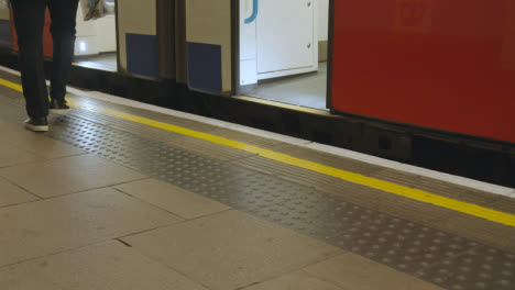 Primer-Plano-Del-Tren-Subterráneo-Que-Llega-A-La-Plataforma-De-La-Estación-De-Metro-En-Londres,-Reino-Unido,-Con-Pasajeros-Que-Se-Bajan-1