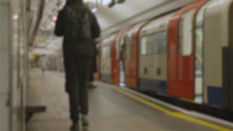 Toma-Desenfocada-Del-Tren-Subterráneo-Que-Llega-A-La-Plataforma-De-La-Estación-De-Metro-En-Londres,-Reino-Unido