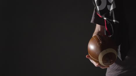 Close-Up-Studio-Shot-Of-American-Football-Player-Holding-Ball-With-Low-Key-Lighting