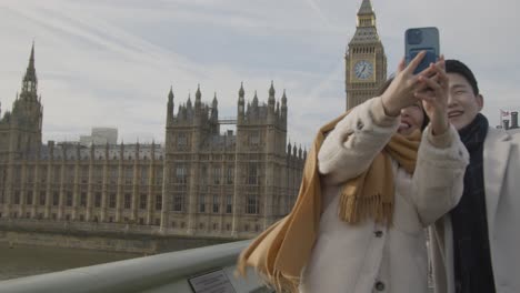 Joven-Pareja-Asiática-De-Vacaciones-Posando-Para-Selfie-Frente-A-Las-Casas-Del-Parlamento-En-Londres,-Reino-Unido-3