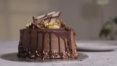 Close-Up-Shot-Of-Person-At-Home-Cutting-Slice-From-Chocolate-Celebration-Cake-On-Table-1