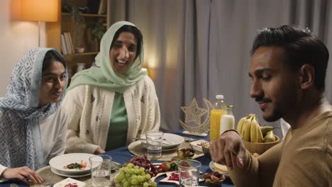 Muslimische-Familie-Macht-Videoanrufe,-Sitzt-Zu-Hause-Am-Tisch-Und-Isst-Iftar-Mahlzeit-Und-Bricht-Während-Des-Ramadan-Täglich-Das-Fasten