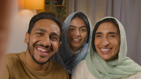 POV-Aufnahme-Einer-Muslimischen-Familie,-Die-Zu-Hause-Am-Tisch-Sitzt-Und-Einen-Videoanruf-Tätigt