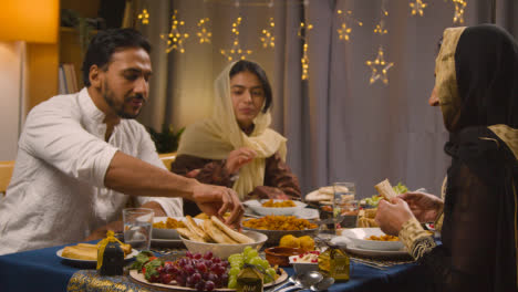 Muslimische-Familie-Sitzt-Zu-Hause-Am-Tisch-Und-Isst-Essen,-Um-Eid-Zu-Feiern