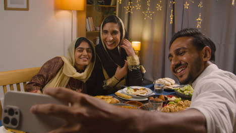 Muslimische-Familie-Sitzt-Zu-Hause-Am-Tisch-Mit-Essen-Zum-Essen-Und-Feiert-Eid-Und-Posiert-Für-Ein-Selfie