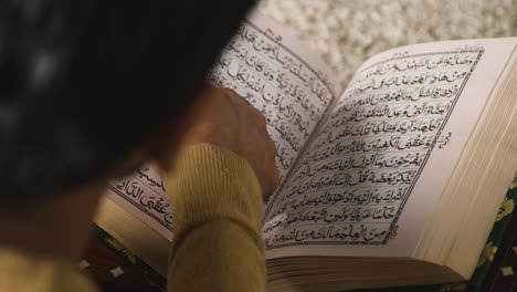 Nahaufnahme-Eines-Muslimischen-Mannes-Zu-Hause,-Der-Auf-Dem-Boden-Sitzt-Und-Aus-Dem-Koran-2-Rezitiert