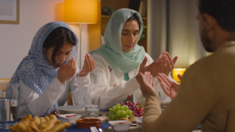 Muslimische-Familie-Sitzt-Zu-Hause-Am-Tisch-Und-Betet-Vor-Dem-Essen