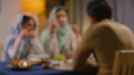 Defokussierte-Aufnahme-Einer-Muslimischen-Familie,-Die-Zu-Hause-Am-Tisch-Sitzt-Und-Gemeinsam-Isst