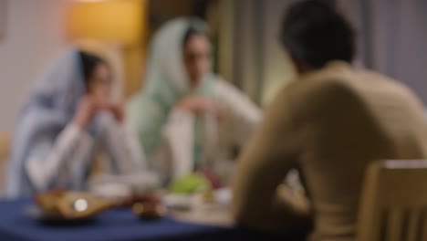 Defokussierte-Aufnahme-Einer-Muslimischen-Familie,-Die-Zu-Hause-Am-Tisch-Sitzt-Und-Gemeinsam-Isst