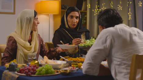 Muslimische-Familie-Sitzt-Zu-Hause-Am-Tisch-Und-Isst-Essen,-Um-Eid-2-Zu-Feiern