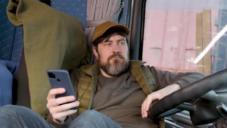 Worker-Wearing-Cap-And-Vest-Tumbado-Lying-On-Truck-Seat-While-Using-Smartphone-1