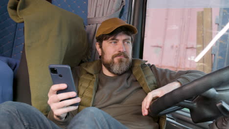 Worker-Wearing-Cap-And-Vest-Tumbado-Lying-On-Truck-Seat-While-Using-Smartphone-2