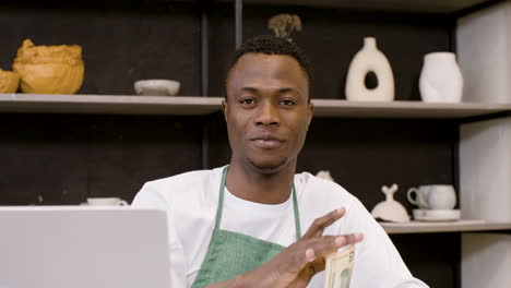 Confident-Male-Small-Business-Owner-Holding-Money-And-Looking-At-Camera-In-The-Pottery-Shop