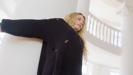Focused-Blonde-Woman-In-Black-Long-Sleeve-Loose-Pullover-Performing-A-Contemporary-Dance-In-The-Studio
