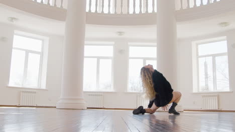 Focused-Blonde-Woman-In-Black-Long-Sleeve-Loose-Pullover-And-Boots-Performing-A-Contemporary-Dance-In-The-Studio-1
