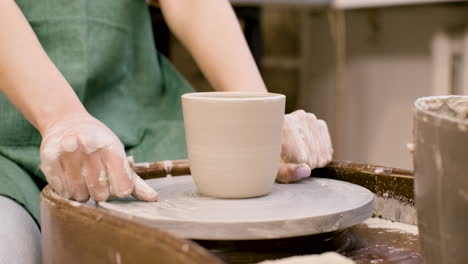 Nahaufnahme-Der-Hände-Eines-Angestellten,-Der-In-Einer-Werkstatt-Ein-Stück-Keramik-Mit-Einem-Faden-Auf-Einer-Töpferscheibe-Schneidet