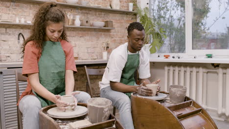 Employees-Wearing-Green-Apron-Modeling-Ceramic-Pieces-On-Potter-Wheel-In-A-Workshop