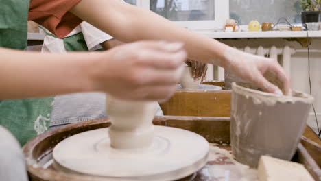 Hands-Of-Employees-Wearing-Green-Apron-Modeling-Ceramic-Pieces-On-Potter-Wheel-In-A-Workshop-1