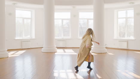 Focused-Blonde-Woman-In-Trench-Coat-And-Boots-Training-A-Contemporary-Dance-In-The-Middle-Of-The-Studio-4