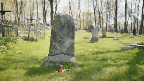 Tombstone-With-A-Red-Rose-And-A-Grave-Candle-On-The-Grass-In-A-Graveyard-On-A-Sunny-Day