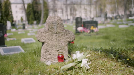 Grabstein-Mit-Einer-Weißen-Blume-Und-Einer-Grabkerze-Auf-Dem-Gras-Auf-Einem-Friedhof-An-Einem-Sonnigen-Tag